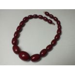 A SINGLE STRAND OF VINTAGE GRADUATED CHERRY AMBER TYPE BEADS, central bead Dia. 2.3 cm,