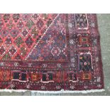 A LARGE RED EASTERN 20TH CENTURY WOOLLEN RUG / CARPET, the central diamond shaped cartouche on a red