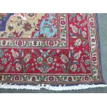 A LARGE EASTERN 20TH CENTURY WOOLLEN RUG, central blue / floral cartouche, contrasting red border,