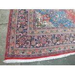 A LARGE EASTERN 20TH CENTURY WOOLLEN RUG, having central cartouche with floral detail, mainly red