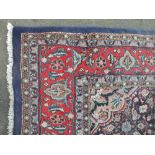 A LARGE EASTERN WOOLLEN RUG / CARPET, with a central floral cartouche on a mainly dark blue ground