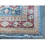 AN EASTERN 20TH CENTURY WOOLLEN RUG / CARPET, the central rectangular cartouche on a mainly blue