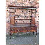 A GEORGIAN OAK WELSH DRESSER, having an open plate rack above a three drawer base, raised on