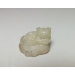 A CHINESE CELADON MODEL OF A RECUMBENT CAT UPON A LOTUS LEAF, finely carved detail, W 3.4 cm, D 2.