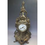 AN ANTIQUE GILT METAL MANTEL CLOCK IN THE ROCOCO STYLE, with cherubic mask head detail, the enamel