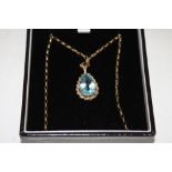A LADIES 9CT GOLD PENDANT SET WITH A LARGE TEARDROP SHAPED BLUE TOPAZ STONE ON 9CT OLD CHAIN