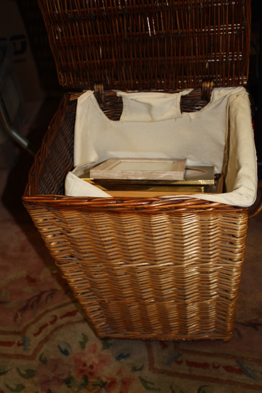 A WICKER BASKET CONTAINING PICTURE FRAMES
