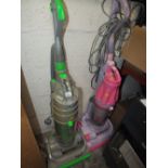 A GREEN DYSON VACUUM TOGETHER WITH A PINK EXAMPLE