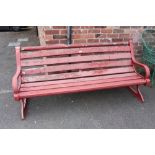 A PAINTED RED GARDEN BENCH BY BOULTON & PAUL LTD WITH CAST BENCH ENDS