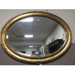 AN OVAL GILT WALL MIRROR - W 81 CM