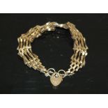 A HALLMARKED 9 CARAT GOLD GATE BRACELET WITH HEART LOCK