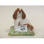 A CERAMIC FIGURE OF A KING CHARLES SPANIEL ON A CUSHION MARKED BASIL MATTHEWS TO BASE
