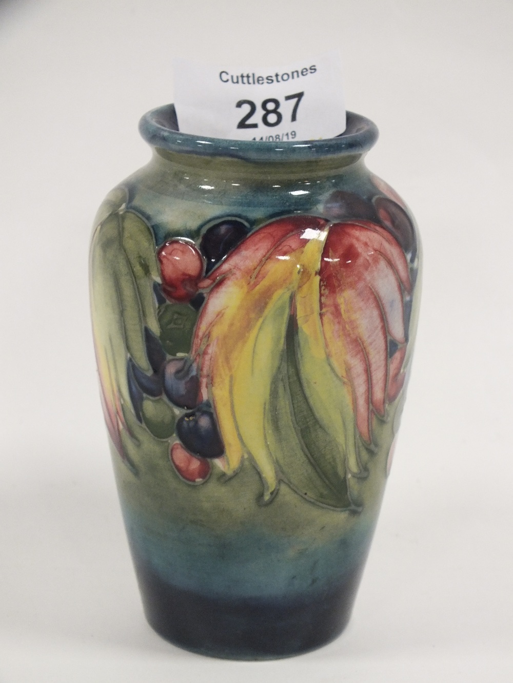 A VINTAGE MOORCROFT VASE DECORATED WITH LEAVES AND BERRIES