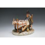 A CAPO DI MONTE FIGURE OF A MAN OVER INDULGING AT THE DINNER TABLE, W 25 cm