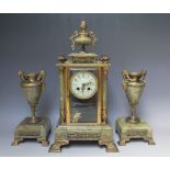 A GREEN ONYX AND GILT METAL FRENCH CLOCK GARNITURE, the four glass clock case with pilasters and urn