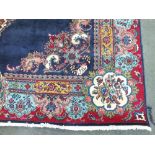 A LARGE EASTERN 20TH CENTURY WOOLLEN RUG, central navy panel with floral cartouche and spandrel