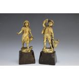 A PAIR OF GILT METAL FIGURES OF A BOY AND A GIRL, Schmidt-felling to the reverse, on polished