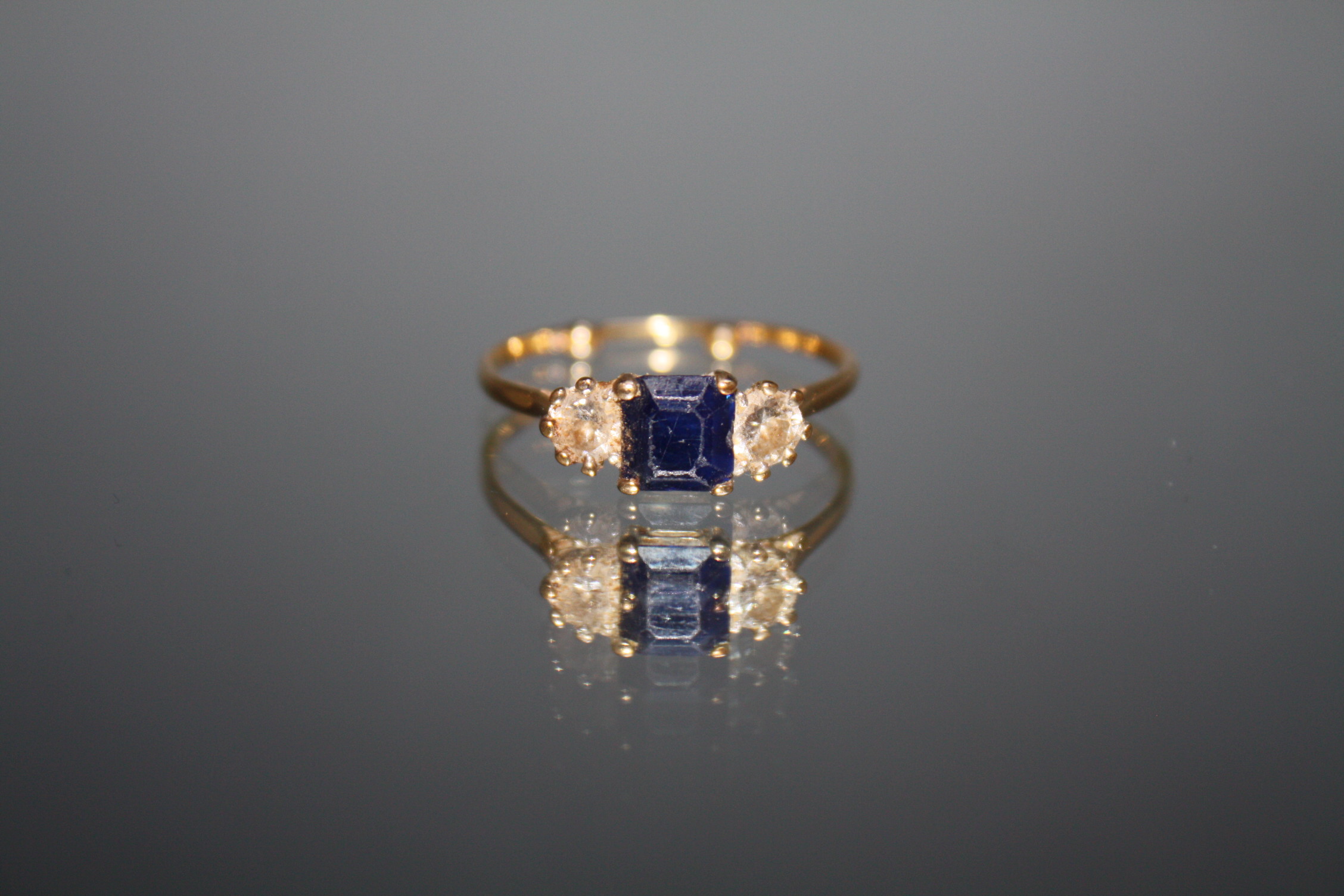 A THREE STONE SAPPHIRE AND DIAMOND RING, set in unmarked yellow metal, each diamond being an