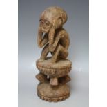 A CARVED WOODEN SEATED TRIBAL FIGURE, H 26 cm