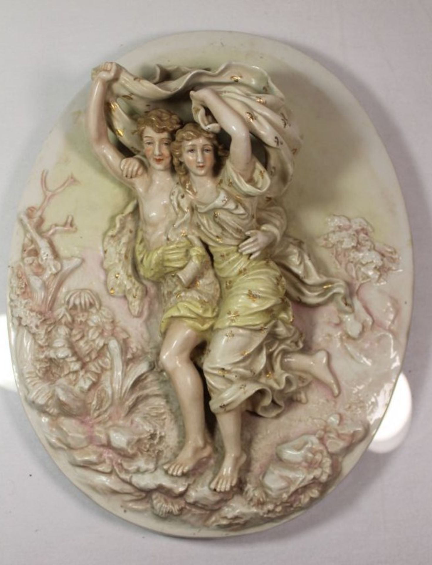 ovale Porzellan-Wandrelief, junges Paar schützt sich vor Regen, Manufaktur unbekannt, farbig