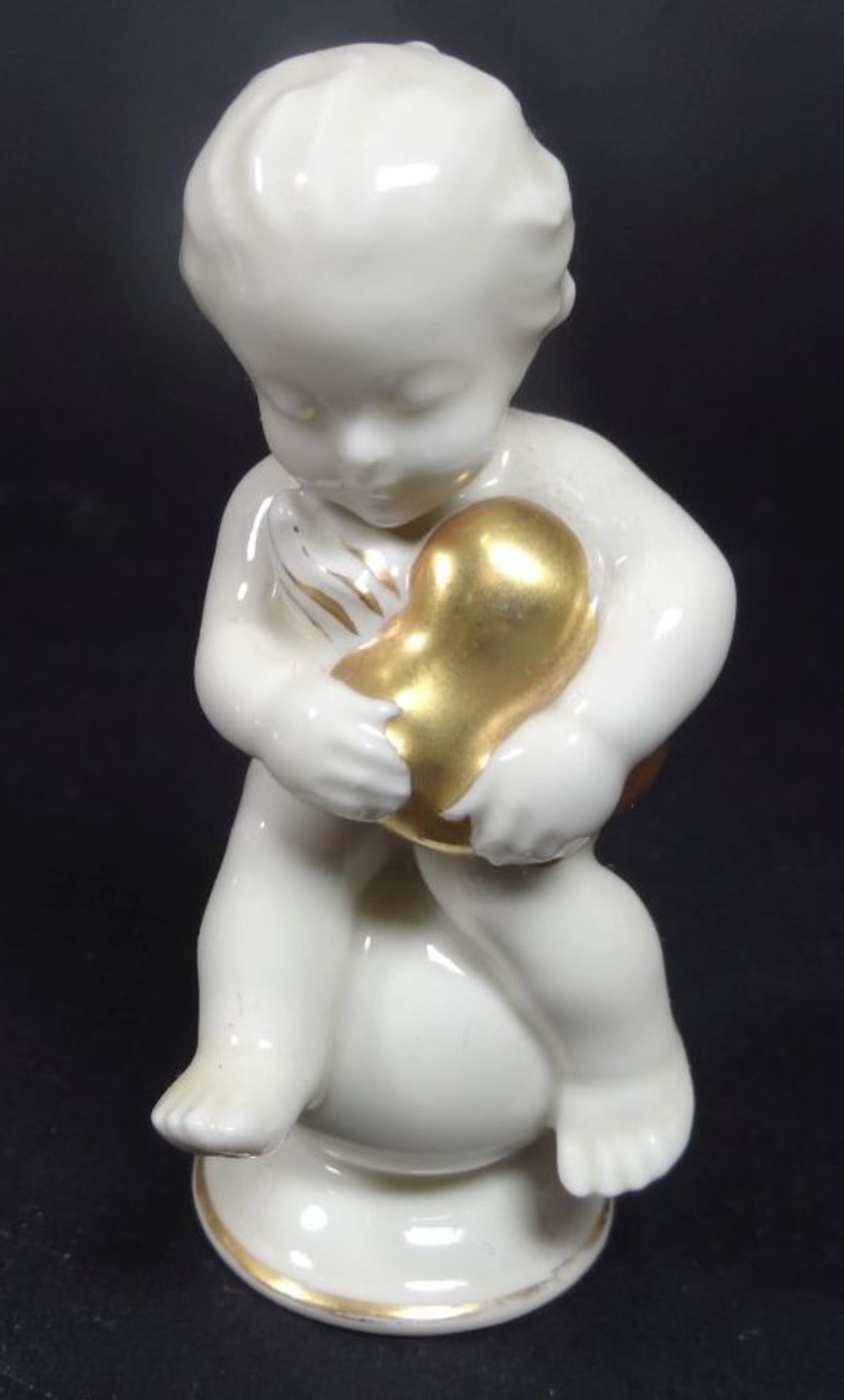 kl. Putto auf Kugel mit goldenem Herz, H-8 cm- - -22.61 % buyer's premium on the hammer priceVAT