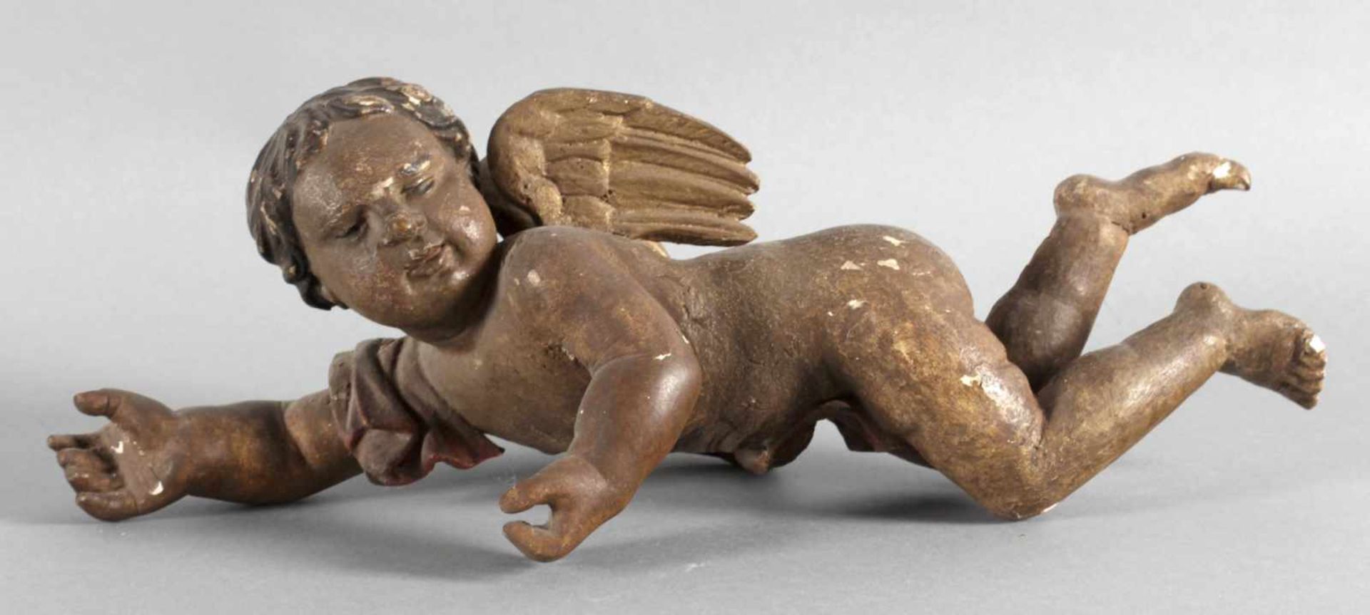 Kleiner Putto, wohl Spanien, 18. - 19. Jh.Holz geschnitzt und gefasst, Alterspatina, L: 37 cm, -