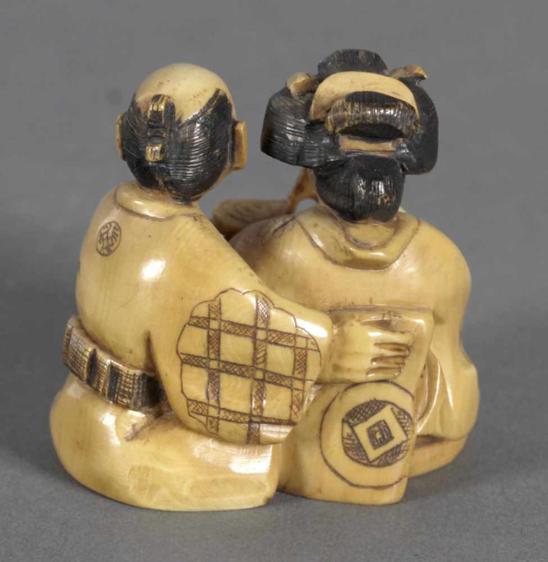 Netsuke eines Paares in Sitzposition, 19. Jh.Elfenbein gelb patiniert, er reicht mit der linken Hand - Bild 2 aus 3