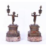 A pair of French patinated bronze and marble mantle ornaments modelled as bronze winged cherubs