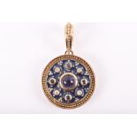 A yellow metal, diamond, and sapphire circular pendant centred with a round cabochon sapphire,
