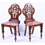 A pair of mahogany pierced back hall chairs with serpentine-fronted seats on turned front legs, 20th