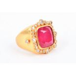 A yellow metal, ruby and diamond ring set with a composite ruby, measuring approximately 13.7 x 13.7