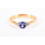 An 18ct yellow gold, diamond, and sapphire ring set with a rounded oval-cut sapphire flanked with