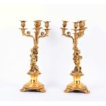 A pair of Louis XV style ormolu candelabra modelled with winged cherubs holding aloft the four armed