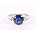 An 18ct white gold, diamond, and sapphire ring set with a natural round-cut blue sapphire of