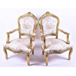 A pair of Louis XV style gilt armchairs with upholstered seating and back depicting Watteau-esque
