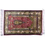 A highly detailed eastern silk fringed rug the central blood red field interspersed with a central