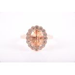 An 18ct rose gold, diamond, and pale orange sapphire ring set with a peach-coloured sapphire of