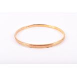 A 9ct yellow gold bangle with engine turned decoration, 7.4cm internal diameter, 21 grams.