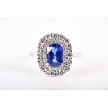 An 18ct white gold, diamond, and sapphire cluster ring set with a rectangular cushion-cut blue