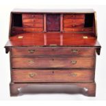 A Georgian mahogany bureau  the drop flap opening to reveal a central cupboard door flanked by eight