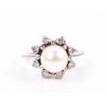 A diamond and pearl cluster ring set with a round white pearl within a star-shaped border of round-