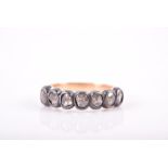 A yellow metal, silver, and diamond half eternity ring with seven individually-set rose-cut