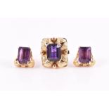 A yellow metal and amethyst ring set with an emerald-cut amethyst with stylised foliate mount,
