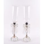 A pair of French cut glass hurricane lamps with faceted stems and bases, with cut glass droplets,
