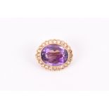 A yellow metal, diamond, and amethyst brooch of oval form, set with an oval-cut amethyst