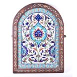 A decorative framed Iznik/Kutahya tile panel of arched form accommodating a total of 12 tiles, circa