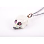 A silver and enamel skull pendant with applied white enamel cabochon ruby eyes, approximately 1.5 cm