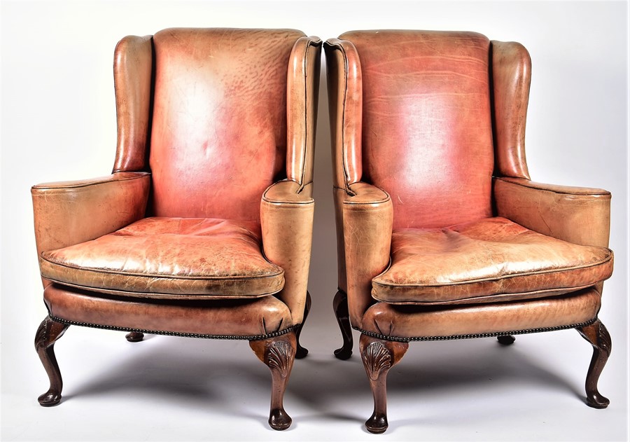 A pair of 20th century leather wingback armchairs with curved arms on four cabriole legs, 82 cm wide