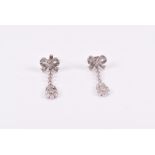A pair of 18ct white gold and diamond drop earrings with a bow-shaped mount, above a line of round-