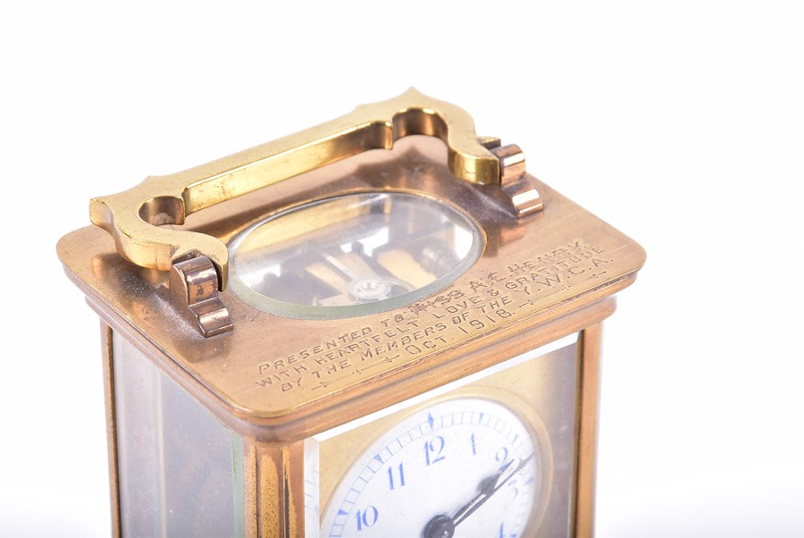 A brass bound Carriage clock with engraved inscription and enameled dial.